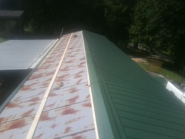 Old rusted panels beside newly installed green metal roofing — Wind Damage Roof Repair by Roofing Brothers in Shippingport