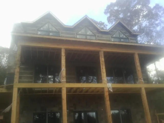 Dormers and porch framing on a large log home under construction — Roof Coating work by our crew in Shippingport