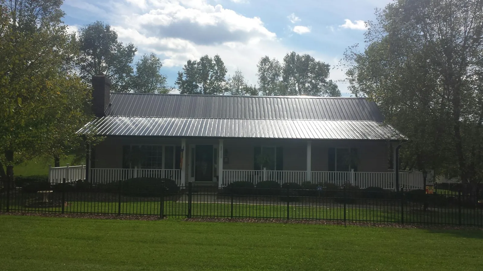 Gray metal roof on a brick ranch with a full width front porch — Gutter Guard Installation work by our crew in Shippingport