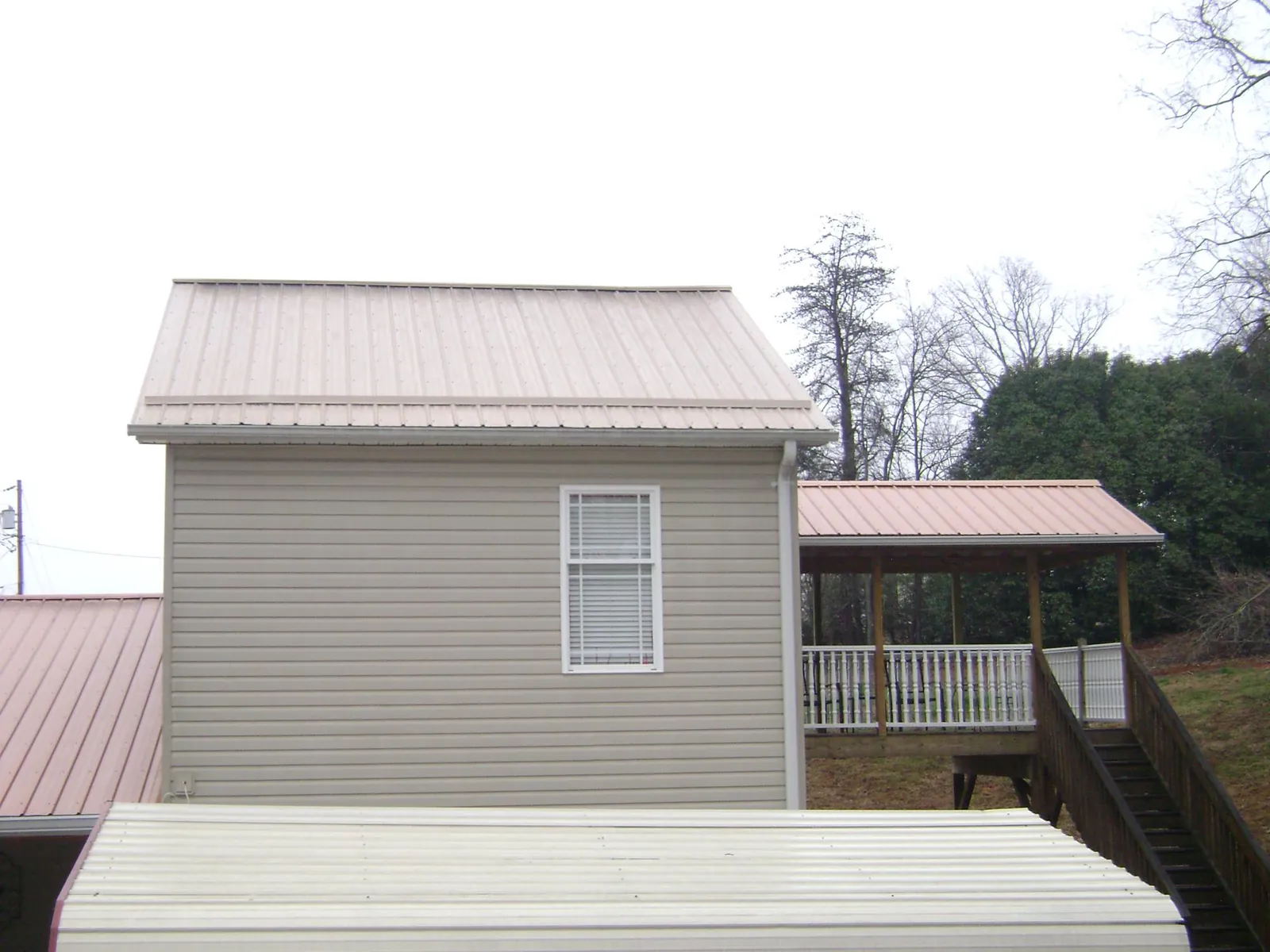 Tan metal roofs on a two story addition and attached porch, from a Roof Replacement job in Shippingport