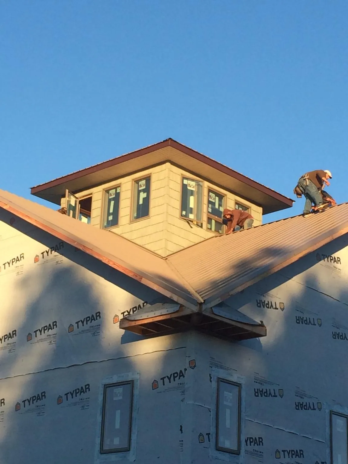 Roofers working around a rooftop cupola on a new metal roof at sunset — Roof Waterproofing in Shippingport by Roofing Brothers